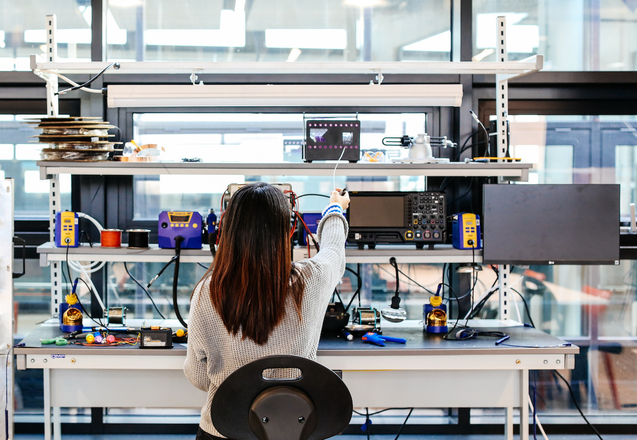 Photo of student sat at an electronics bench with test equiptment on it