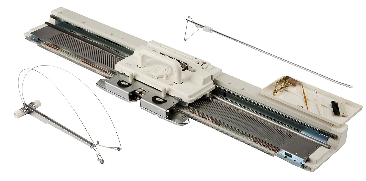 A picture of the silver reed knitting machine, showing different accessories laid out beside the needle bed.